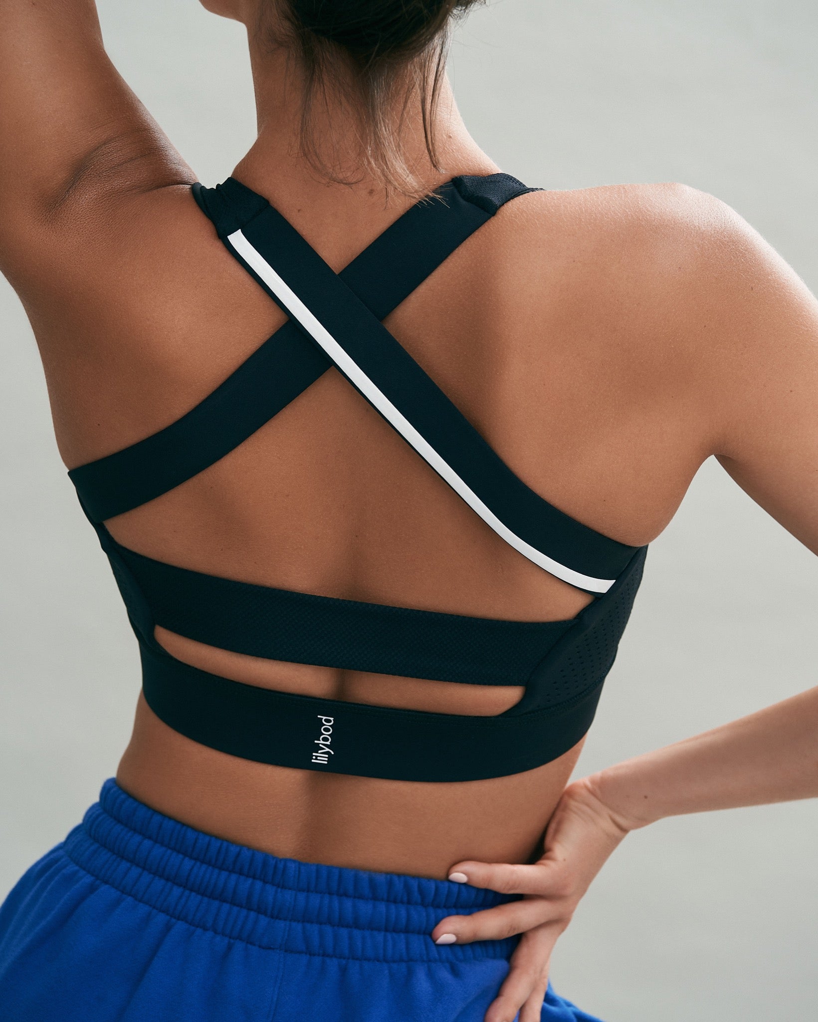 A woman wearing a black sports bra and blue sweatpants.