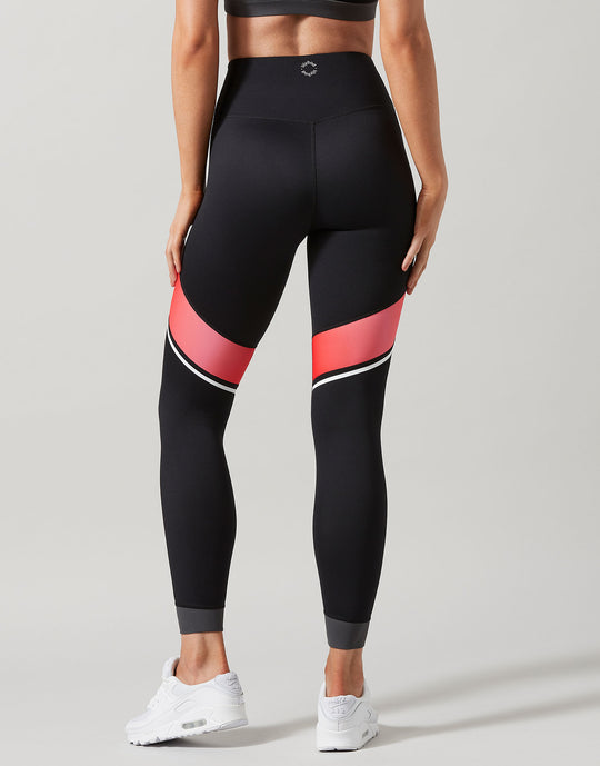 Black leggings with red and white accents worn by a person on a gray background