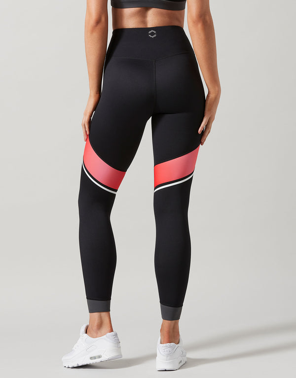 Black leggings with red and white accents worn by a person on a gray background