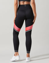 Black leggings with red and white accents worn by a person on a gray background