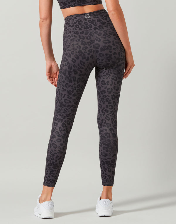 Person wearing black leopard print leggings on a light gray background