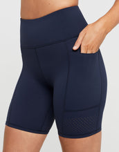 Close up of navy blue athletic shorts worn by a person on a light gray background