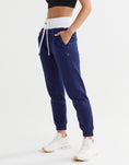 Woman wearing dark blue and white sweatpants side view