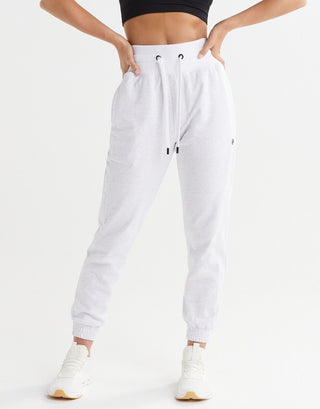 A pair of relaxed fit sweatpants in misty grey marle and bright white, shown in a standing position with hands on hips.