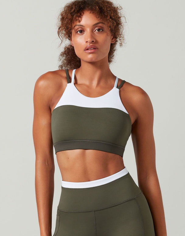 A sports bra in colors tarmac, white, and blue with contrast color block design, featuring a high-scooped neckline and strappy back.