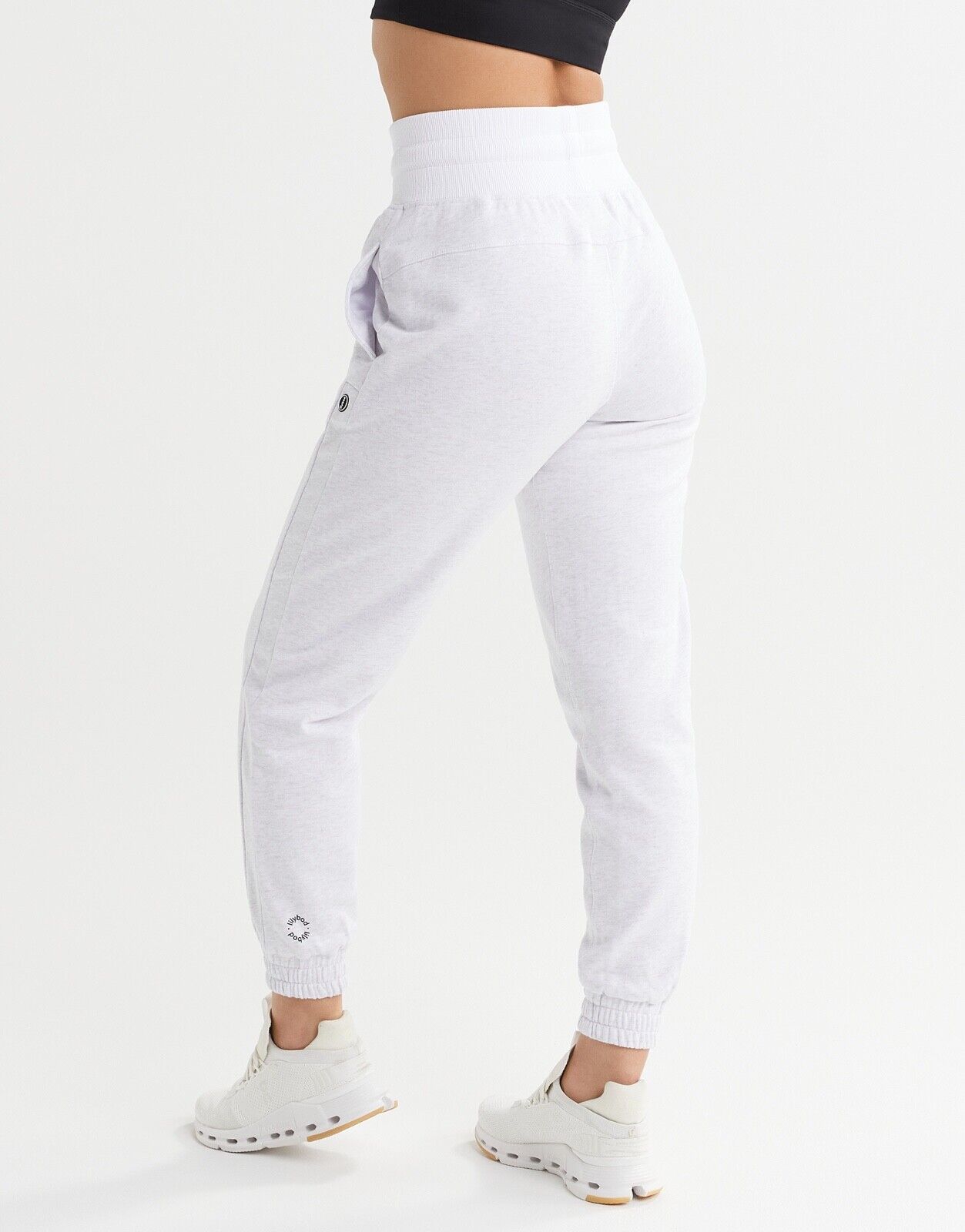 A woman wearing light grey sweatpants and white runners.
