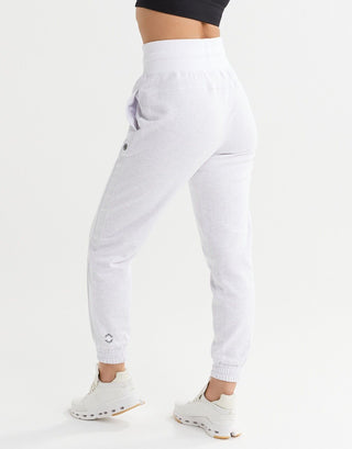 A woman wearing light grey sweatpants and white runners.