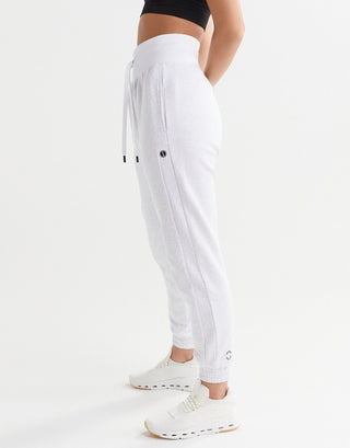 A woman wearing light grey sweatpants on a white background