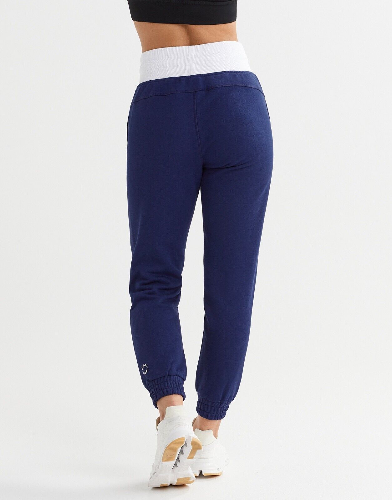 Rear view of a woman wearing blue and white joggers and white shoes