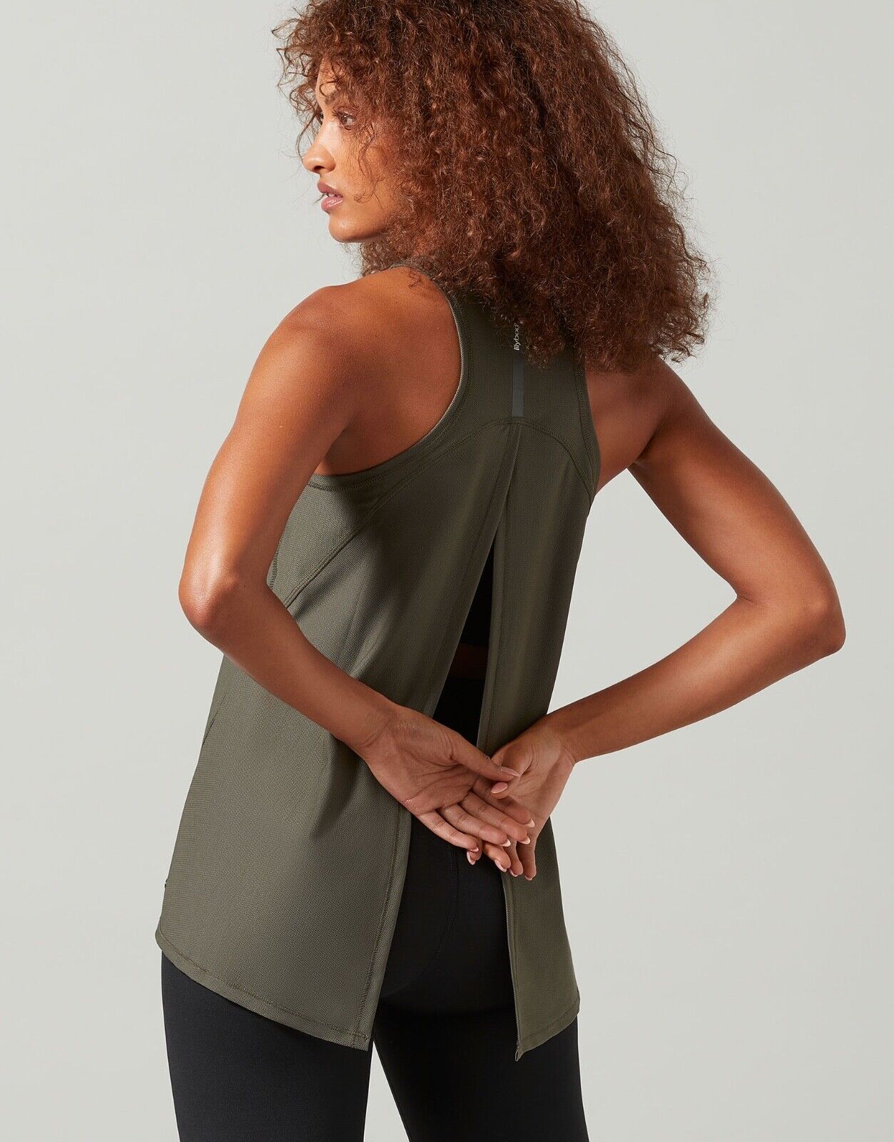 A woman wearing a green Lilybod Kendell Activewear Tank Tarmac top with a tie-up back.