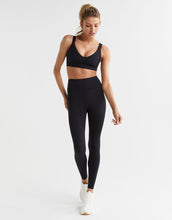 Woman wearing a black athletic outfit on a white background