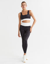 Woman wearing a black and white athletic outfit on a light gray background