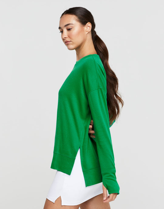 Woman wearing a green sweater and white skirt on a light gray background