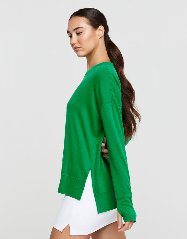 Woman wearing a green sweater and white skirt on a light gray background