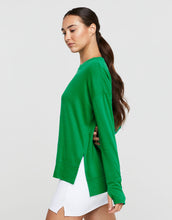 Woman wearing a green sweater and white skirt on a light gray background