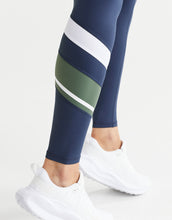 Close up of navy leggings with green and white stripes worn with white sneakers on a light grey background