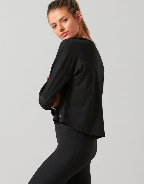 Woman wearing a black jacket and leggings on a gray background