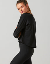 Woman wearing a black jacket and leggings on a gray background