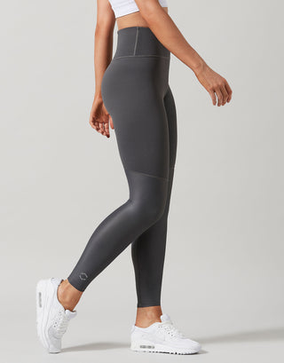 Person wearing gray leggings and white sneakers on a plain background