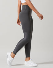 Person wearing gray leggings and white sneakers on a plain background