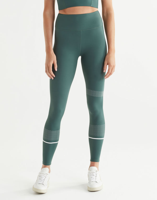 Woman wearing green sports leggings with white accents on a white background