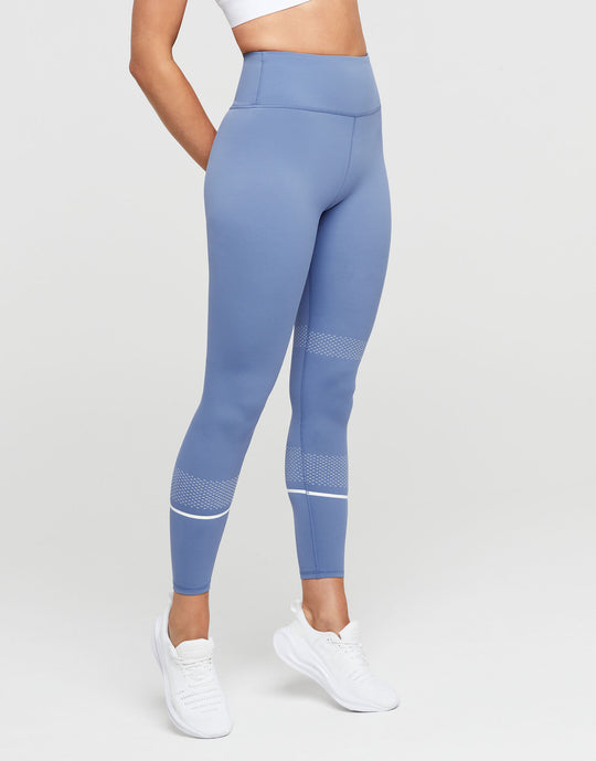 Blue leggings with white accents worn by a person on a light gray background