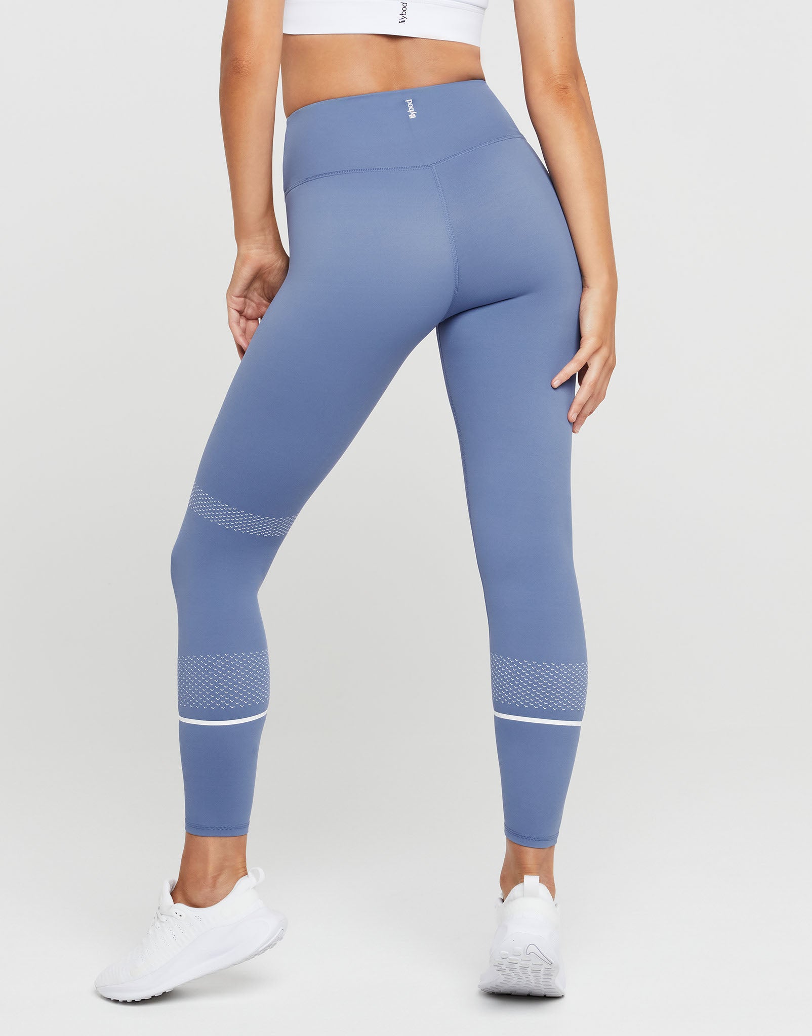 Person wearing blue leggings with white accents on a white background