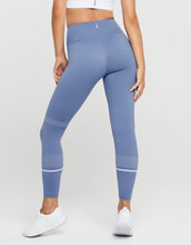 Person wearing blue leggings with white accents on a white background