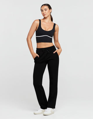 Woman wearing a black sports bra and black pants on a white background