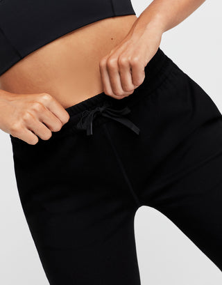 Person wearing black pants on a plain background