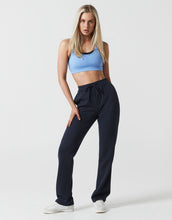 A model wearing navy sweats and a light blue sports bra