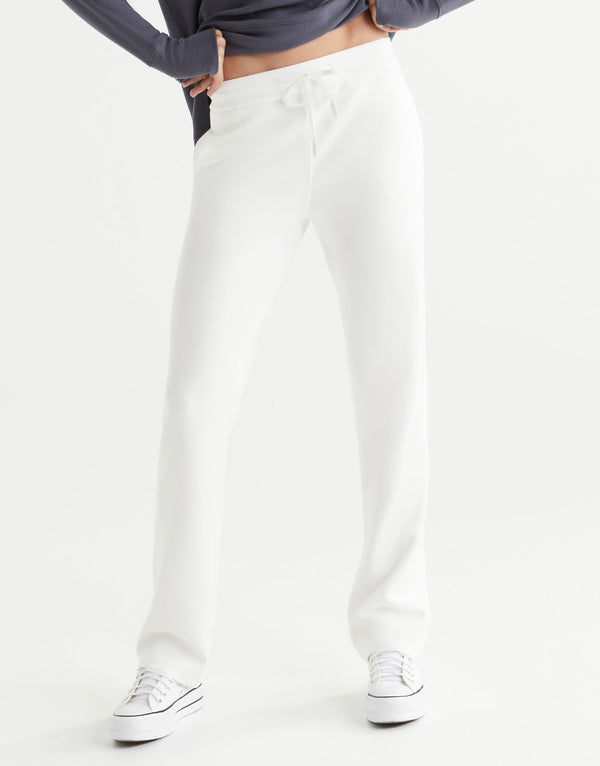 Person wearing white pants and a blue top on a white background