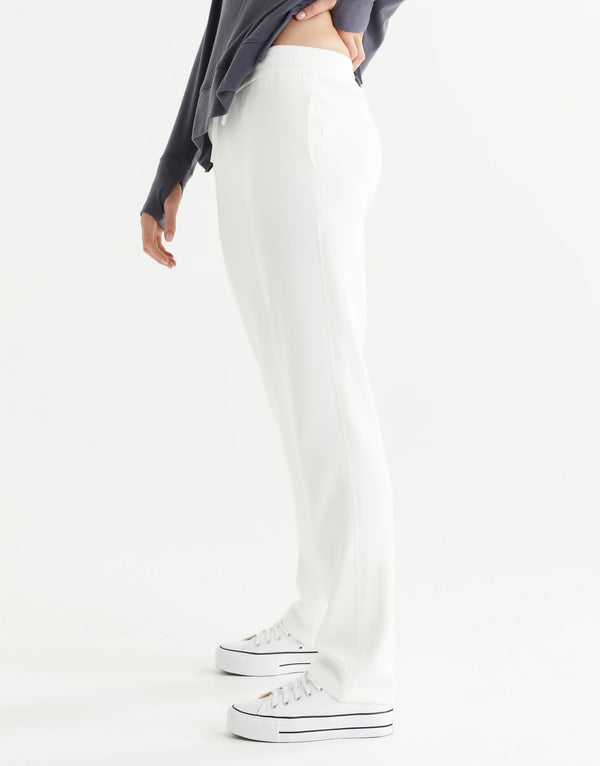 Person wearing white joggers and white sneakers on a white background