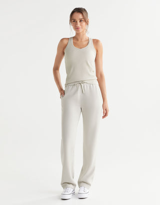 Woman wearing a beige tank top and pants on a white background