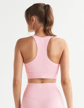 Person wearing a pink sports bra and leggings on a light gray background