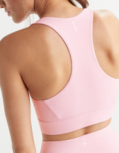 Close-up of a pink sports bra on a person against a white background