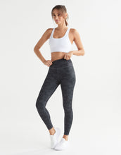 Woman wearing a white sports bra and dark gray leggings on a white background