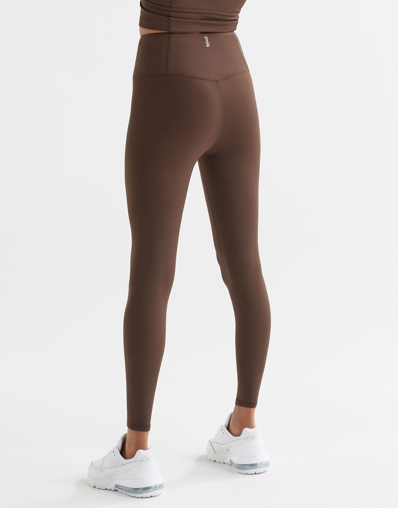 A woman wearing Lilybod Astrid Oak leggings and white sneakers.