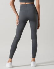 Person wearing dark gray leggings on a light gray background