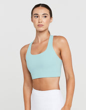 Woman wearing a light blue sports bra against a plain background