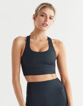 Woman wearing a black sports bra and leggings on a white background