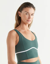 Woman wearing a green athletic top with a white stripe on a light gray background