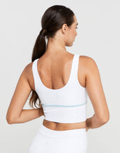 Woman wearing a white sports bra with a subtle design on a plain background