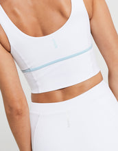 White sports bra with a light blue band on a neutral background