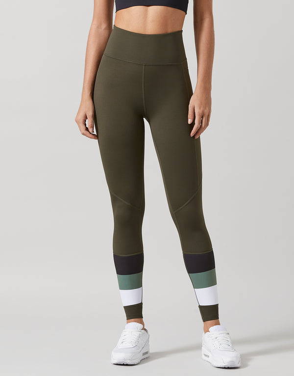 Person wearing green leggings with color-blocked design on a plain background