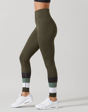 Olive green leggings with color-blocked design worn by a person on a light gray background