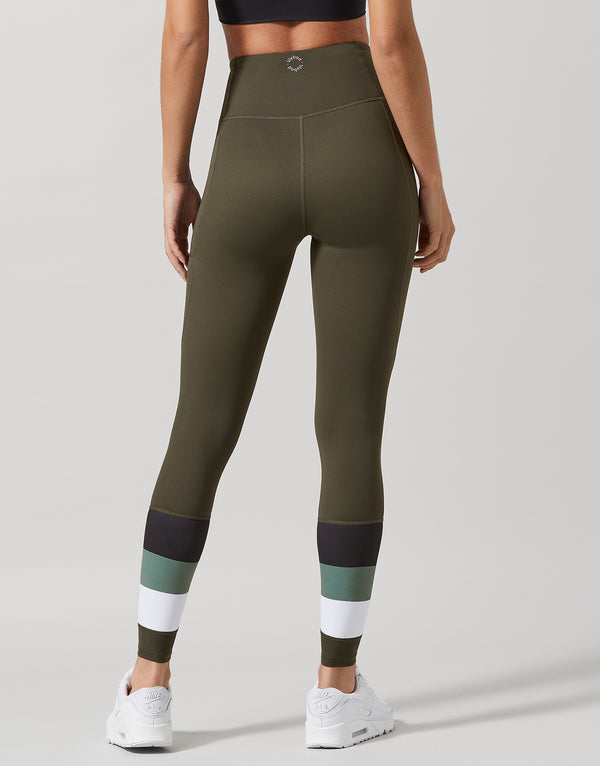 A woman wearing green leggings with color-blocked design on a gray background