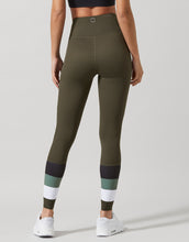 A woman wearing green leggings with color-blocked design on a gray background