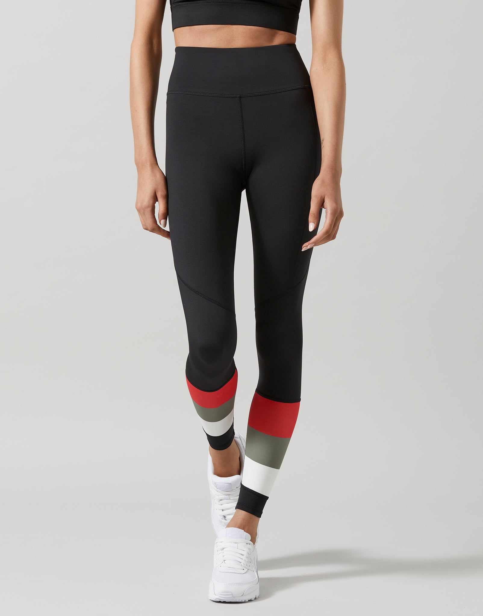 Person wearing black leggings with red and gray accents on a light gray background