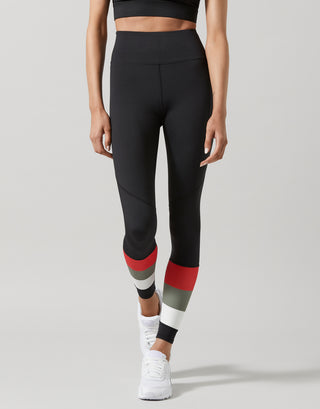 Person wearing black leggings with red and gray accents on a light gray background